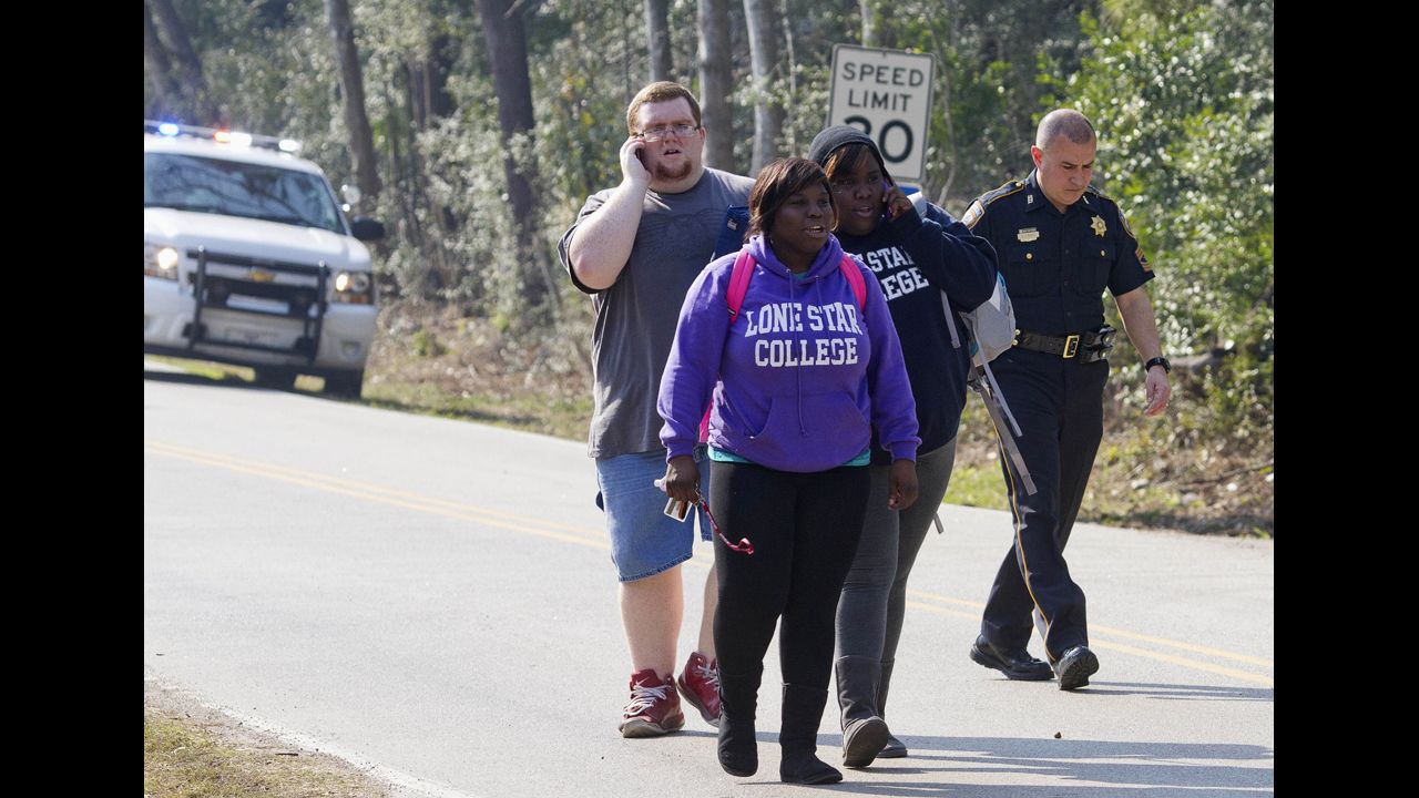 Students evacuate the area with a sheriff's deputy near the college's North Harris campus. There were more than 10,000 students on the campus at the time of the shooting, spokesman Jed Young said.