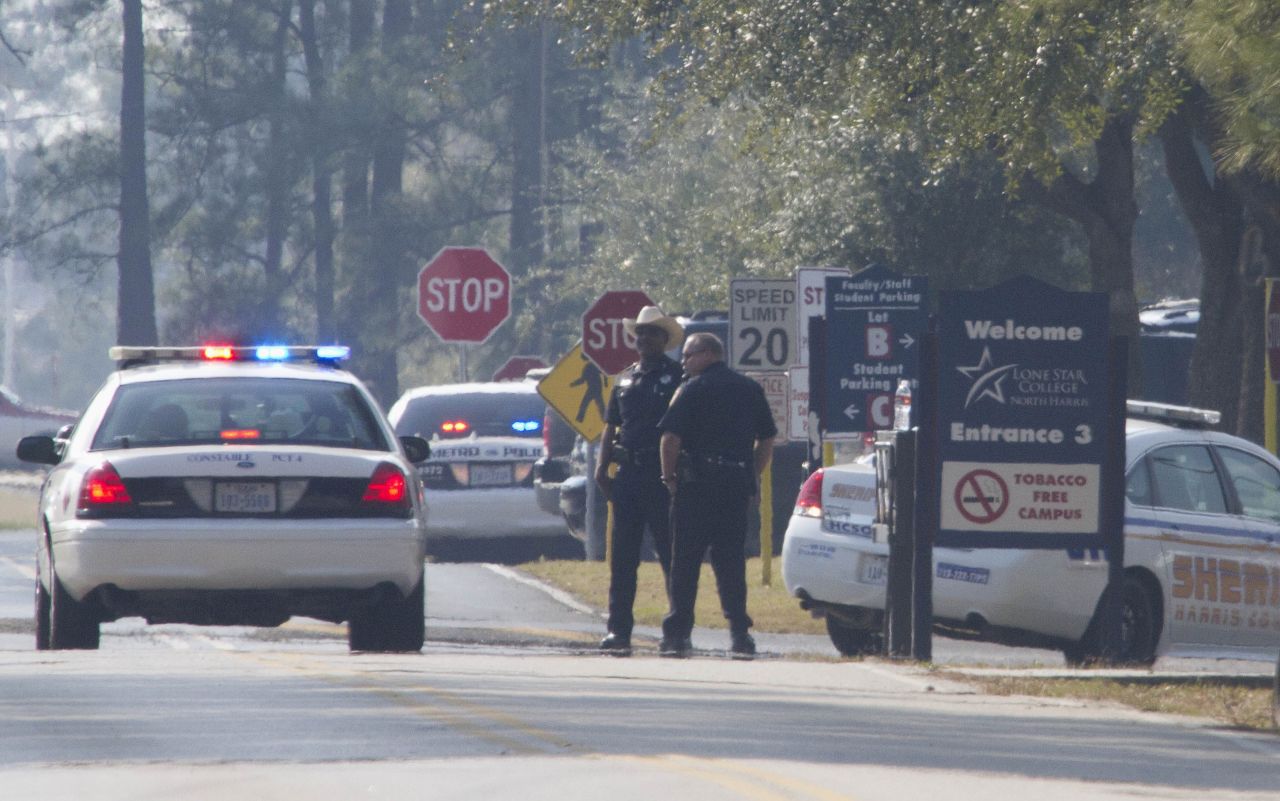 Sheriff's deputies and Houston police stand on the street in front of the campus.