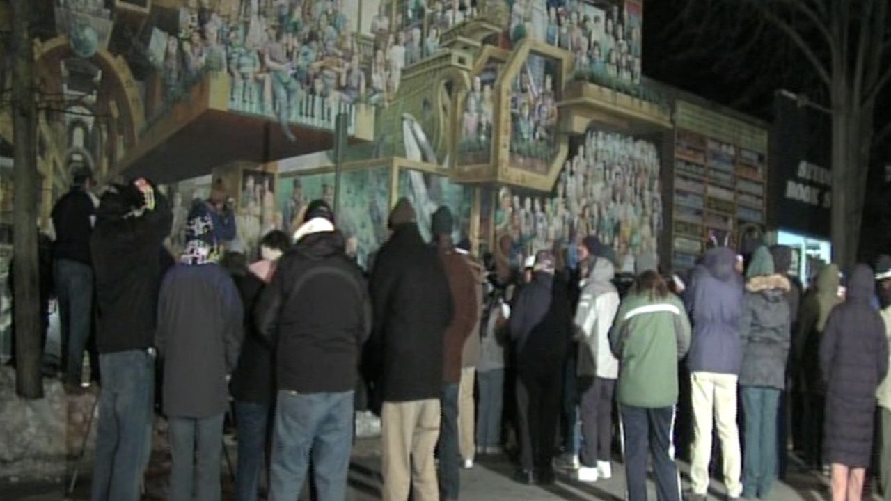 Loyal fans gather Tuesday at a mural depicting late football coach Joe Paterno and other Penn State luminaries.