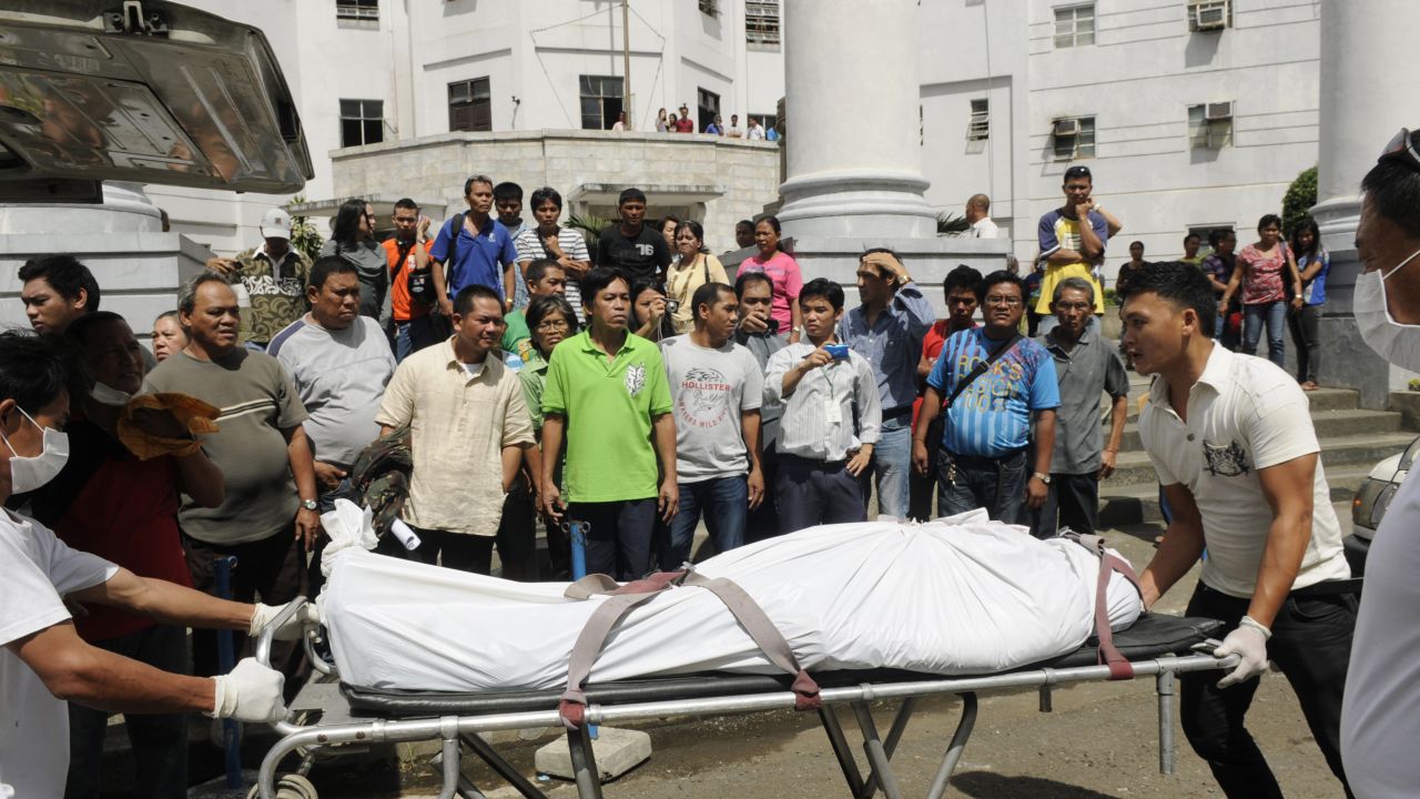 Funeral parlor workers push a stretcher carrying one of the two people killed by a Canadian national on Tuesday.