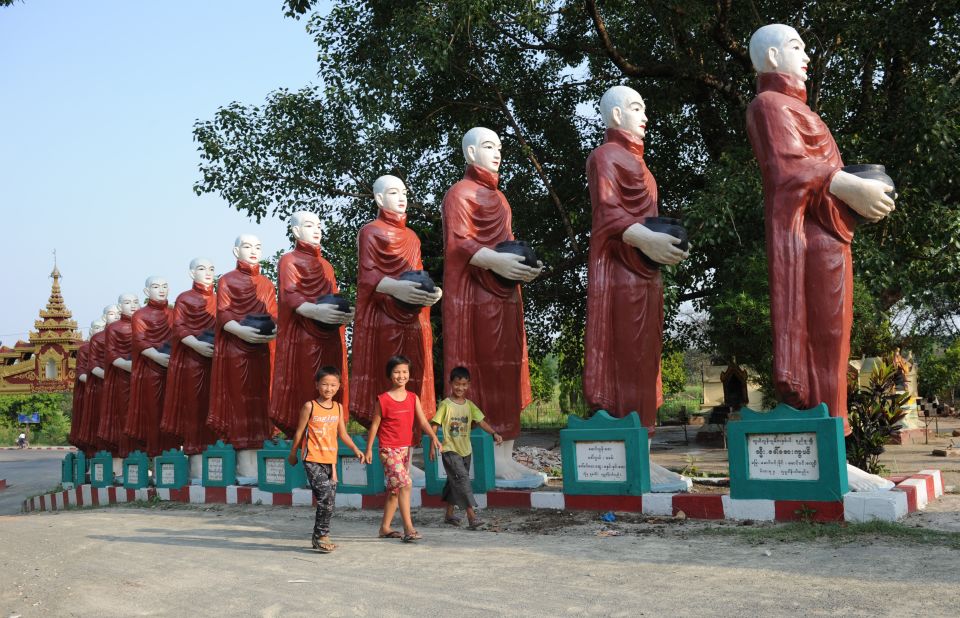 Children walk past giant statues of monks at a pagoda in the town of Myitkyina, in Kachin province in May 2012.