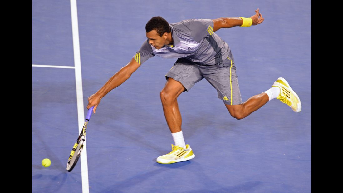 France's Jo-Wilfried Tsonga scoops up a return to Switzerland's Roger Federer during their men's singles match on January 23. Federer defeated Tsonga 7-6 (4), 4-6, 7-6 (4), 3-6, 6-3.