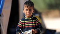 A Syrian boy holds his plate of food in a newly built refugee camp at the village of Qah, near the Turkish border, on October 14, 2012.