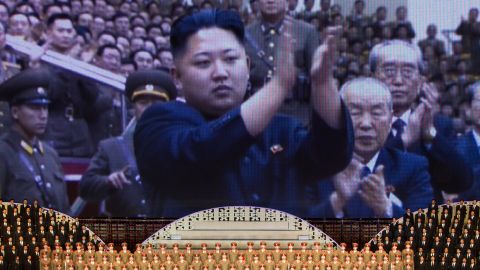 North Korean performers sit below a screen showing images of leader Kim Jong Un in Pyongyang in April 2012.