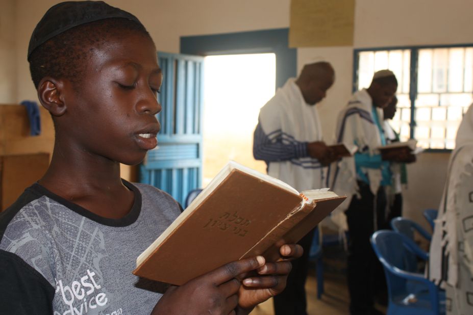 14-year-old Kadmiel Izungu Abhor reads from a prayer book wearing his kippah. He says that one day he wants to take a pilgrimage to Israel. (Courtesy: Chika Oduah.)