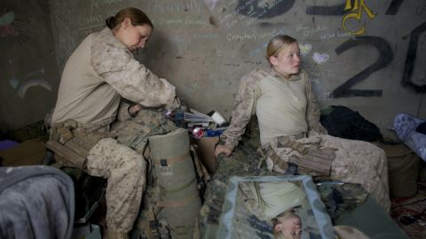 Hospital Corpsman Shannon Crowley packs for a mission as Lance Cpl.. Kristi Baker sits on her bed in 2010 in Afghanistan. 

