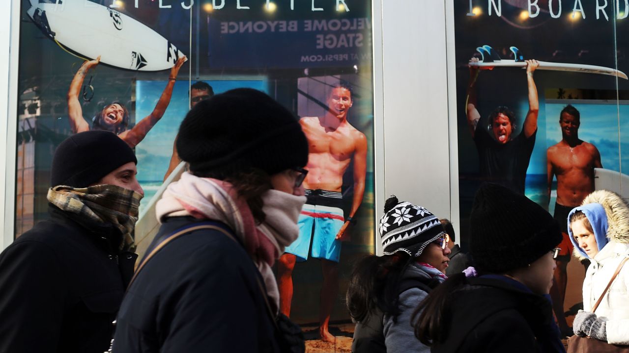 A surfer store with guys in swimwear seems an especially cruel sight for these bundled-up New Yorkers on Tuesday, January 22, as frigid temps hit the region.