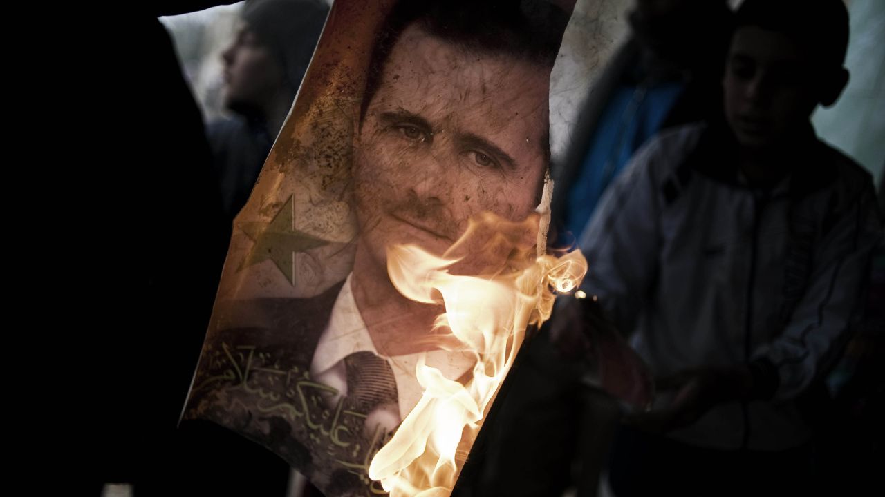 Member of Free Syrian Army holds burning portrait of President Bashar al-Assad in Al-Qsair, January 25, 2012.