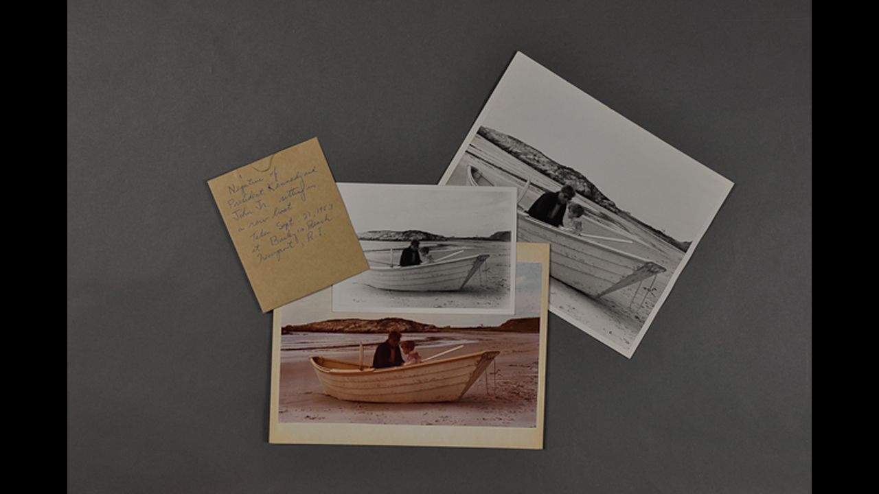 Color photograph of JFK with John Jr. sitting in a rowboat at Bailey's Beach, Newport, Rhode Island, September 1963.