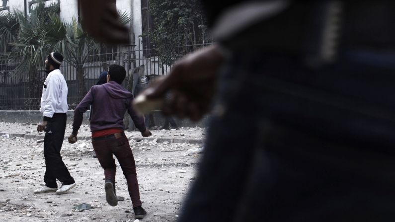A protester throws a rock at riot police in Cairo.
