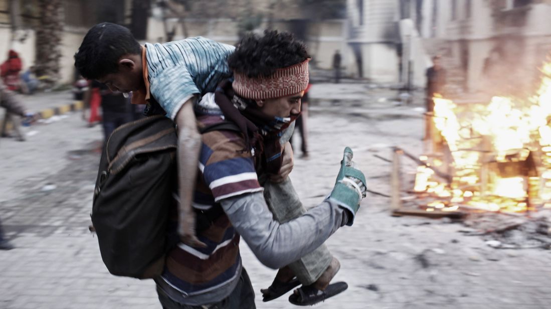 An Egyptian protester carries an injured boy away from clashes with Egyptian riot police on January 26, in Cairo.