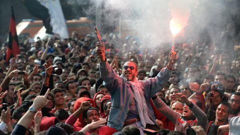 An Egyptian fan of Al-Ahly football club fires celebratory shots in the air and lights a flare as club supporters celebrate outside its headquarters in Cairo on January 26.