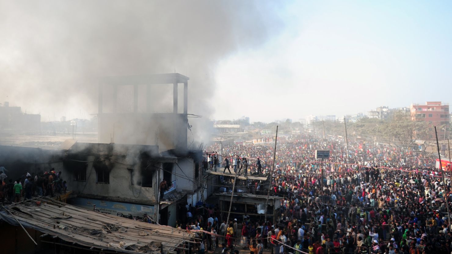 A crowd watches as firefighters and volunteers attempt to extinguish a blaze at a garment factory in Dhaka on Saturday.