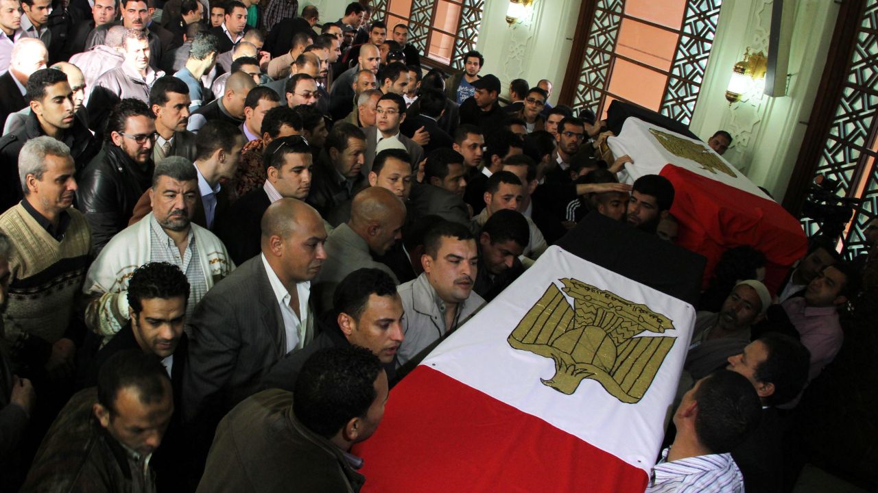 Egyptian policemen and relatives on January 27 gather upon the arrival of the coffins of their colleagues killed in the violence one day earlier in Cairo.