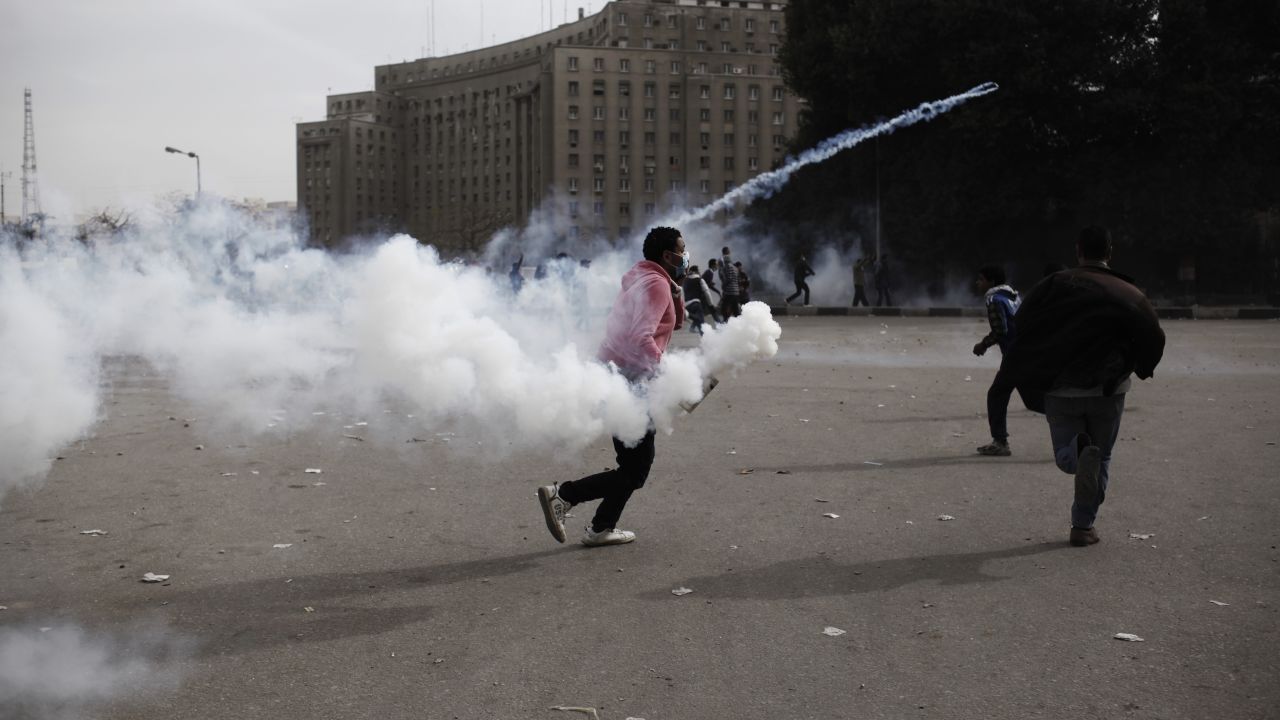 A protester throws a tear gas canister toward riot police in Cairo's Tahrir Square on Sunday, January 27. 