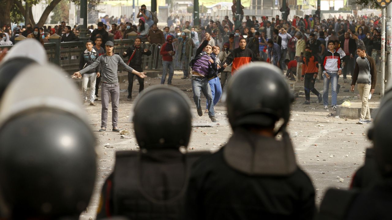 Egyptian protesters throw stones toward riot police on January 27 in Tahrir Square.