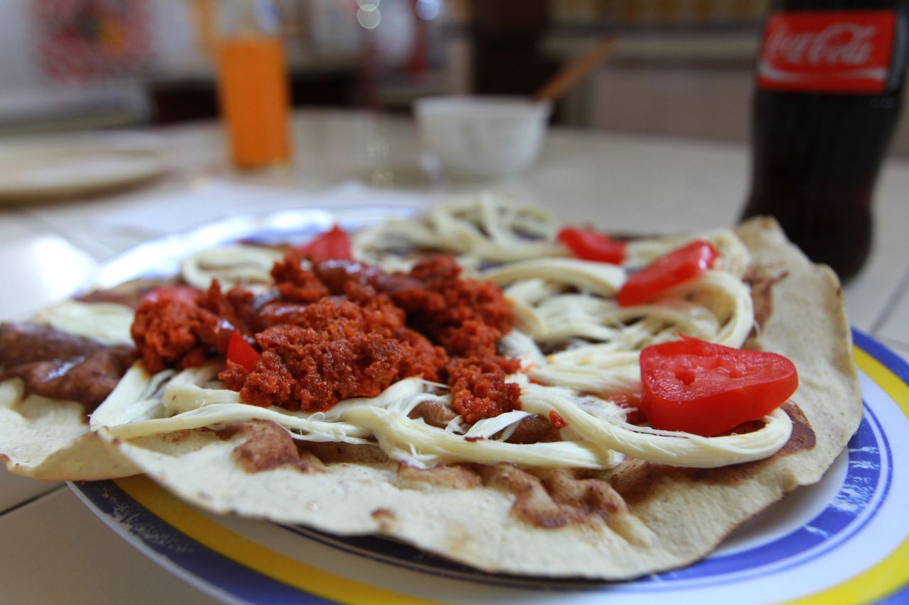 Tlayudas are a Oaxacan specialty, an open-face crisped tortilla with toppings such as beans, cheese, tomatoes and chorizo. 