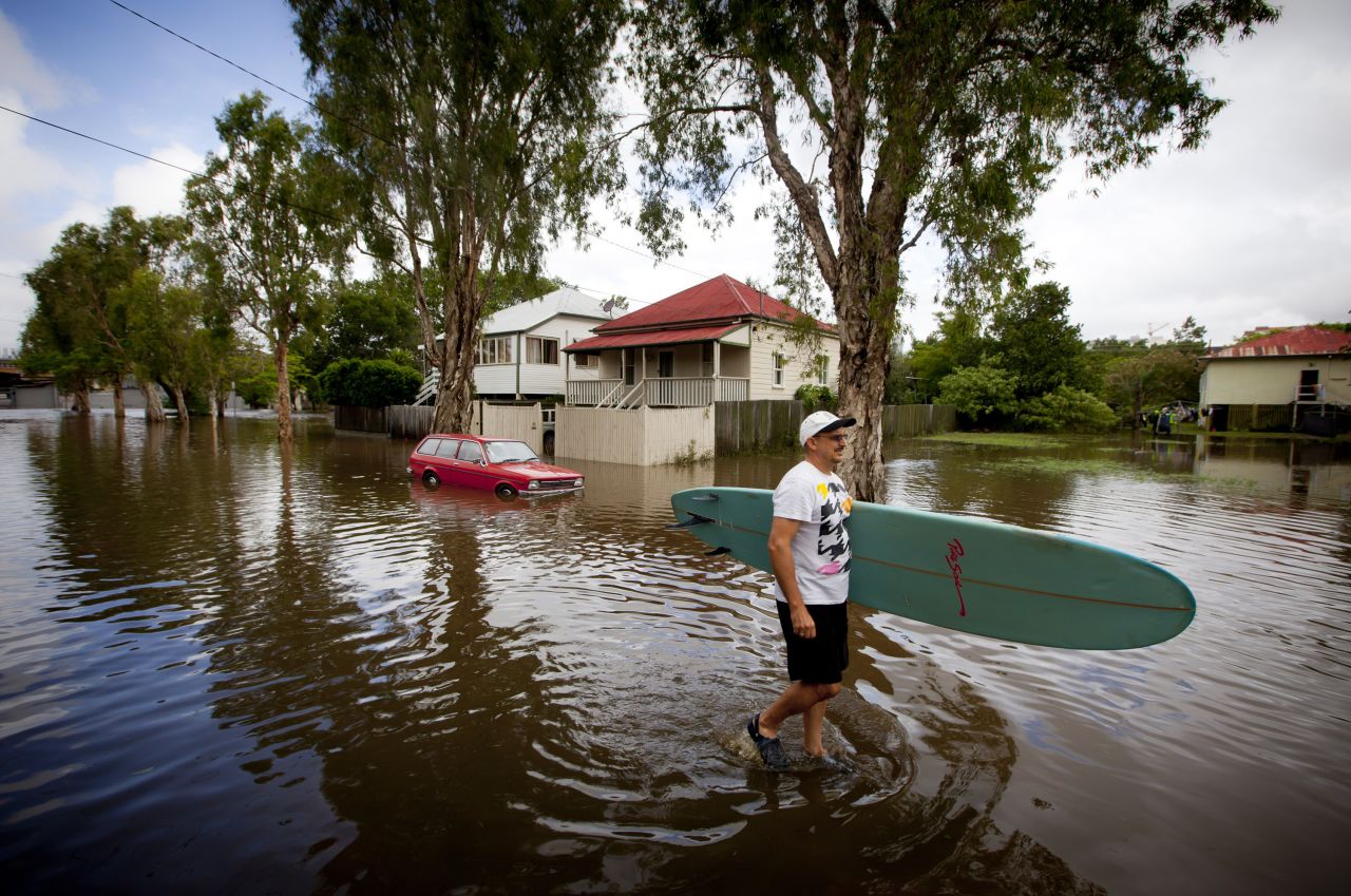Roger Barnes rescues a friend's surfboard from a flooded home in the inner Brisbane suburb of Newmarket in Queensland on Monday, January 28. 
