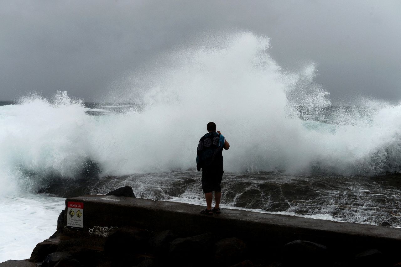 A man films large waves battering the coast on Sunday, January 27, at Snapper Rocks in Coolangatta on the Queensland and New South Wales border.