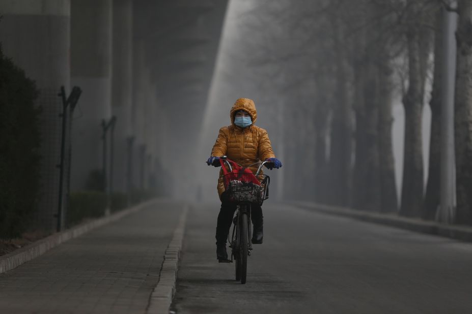 A woman wears a mask and rides her bike on January 23.