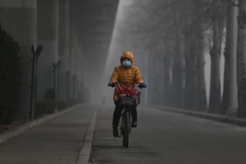 A woman wears a mask and rides her bike on January 23.