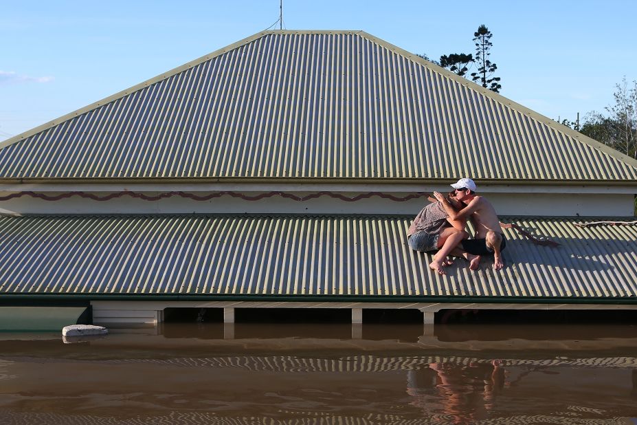  A man comforts his daughter on the roof of their flooded house in Bundaberg on January 29. More than 2,000 homes have been inundated with water in the town, the mayor said.
