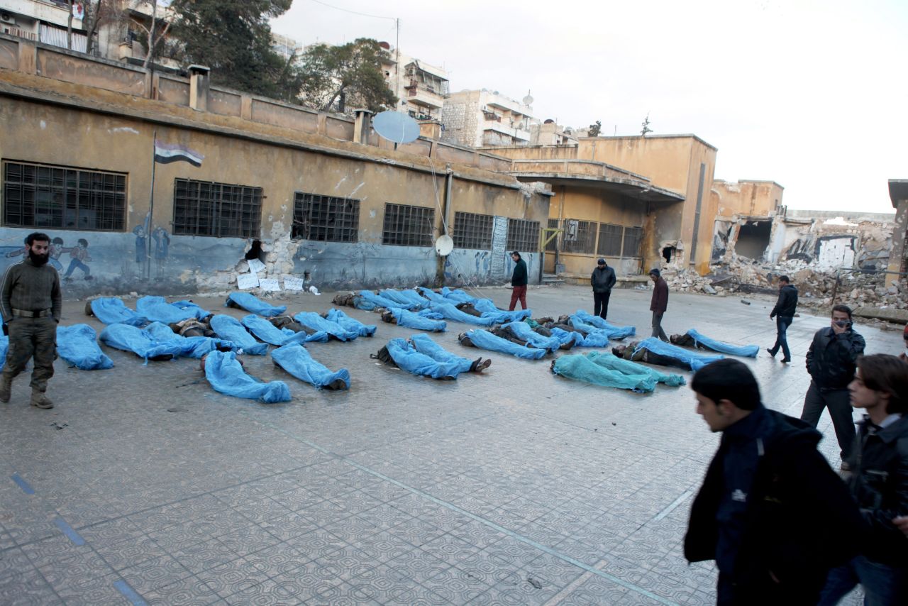 Bodies in blue plastic bags lie in a school courtyard while residents try to identify missing relatives.