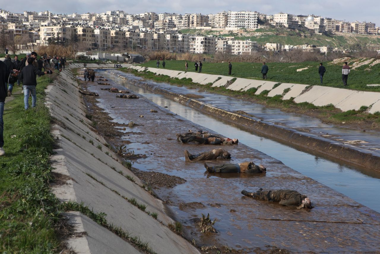 Locals gather on the banks to view the corpses.