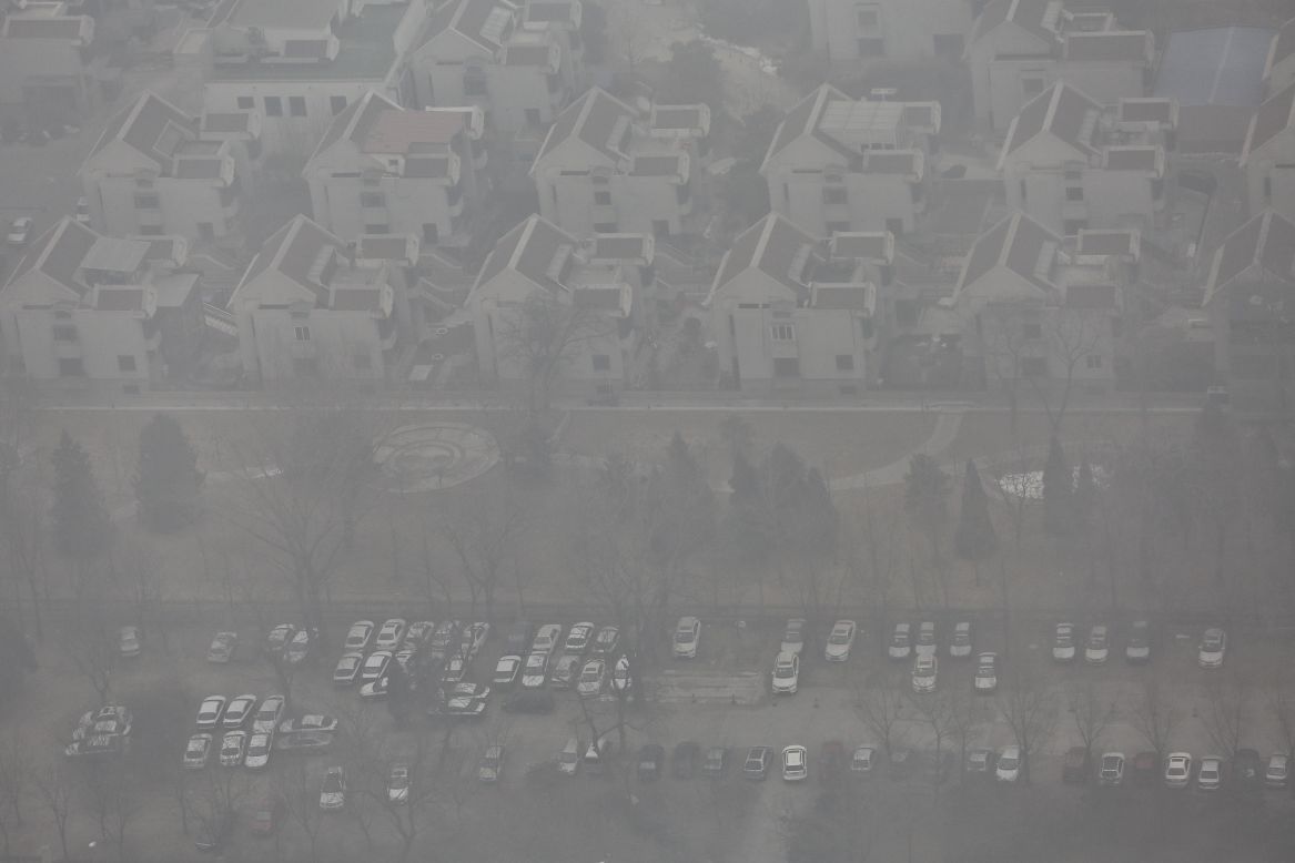 Residential buildings and cars can be made out through the smog in Beijing on January 30.
