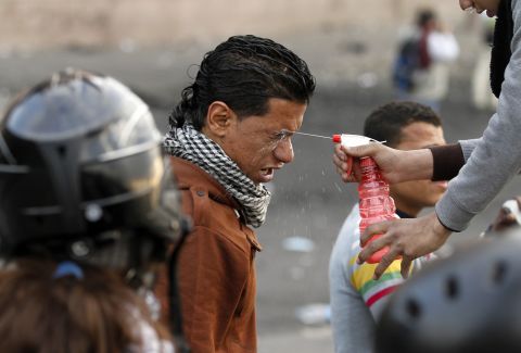 A protester sprays water into the eyes of a man after his exposure to tear gas during clashes with police near Cairo's Tahrir Square on Tuesday, January 29.
