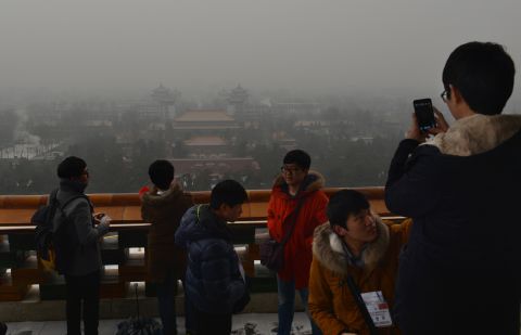 Japanese tourists take photos from Jingshan Park as smog continues to shroud Beijing on January 31. The smog also forced the cancellation of airline flights and highway closures in parts of Beijing, Chinese state media reported.