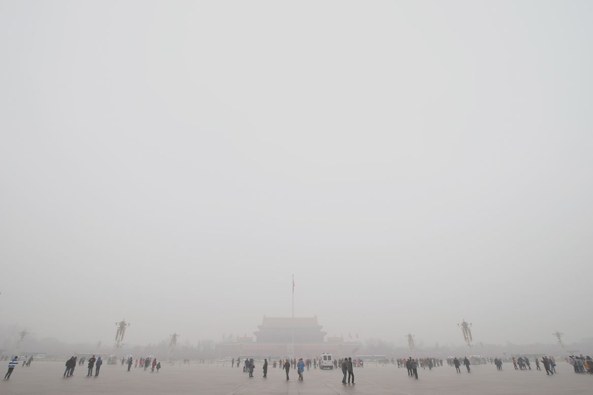 Tourists visit smog-shrouded Tiananmen Square.