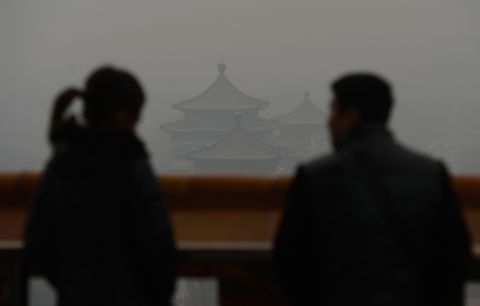 Chinese tourists look at the barely visible historic buildings in Jingshan Park.