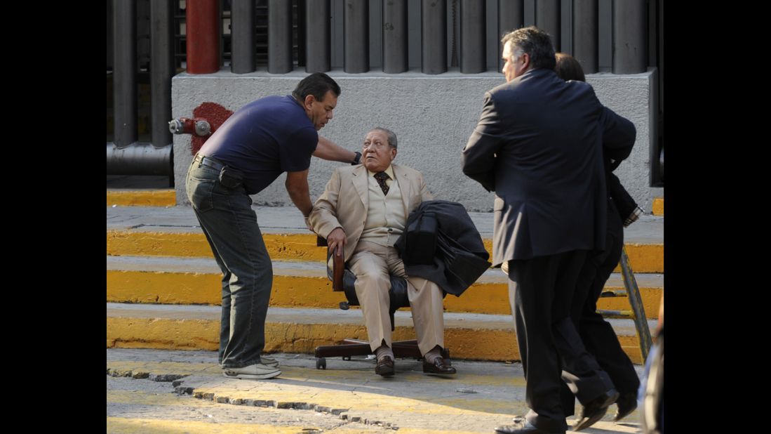 A man at the scene of the blast is helped using a rolling chair near the scene of the explosion.
