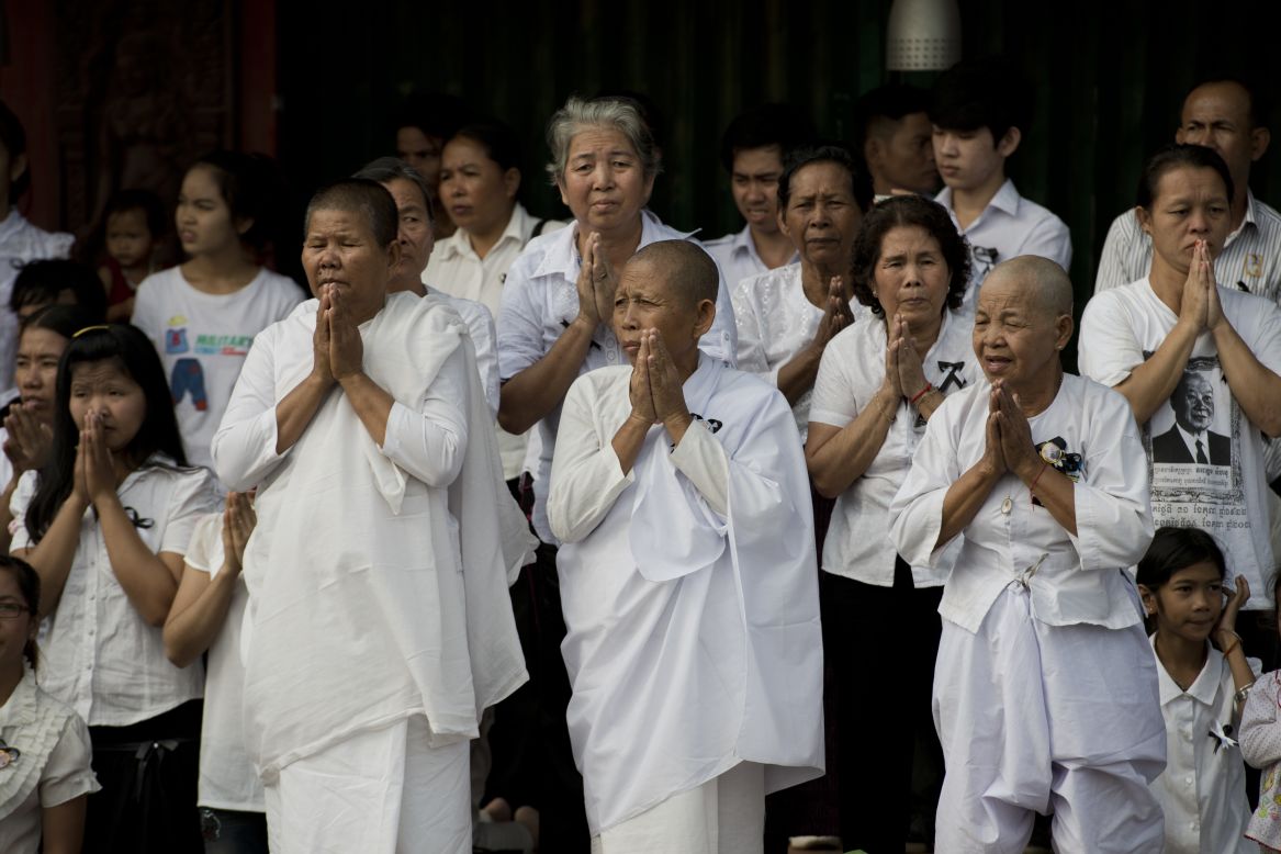 Cambodians pray as they look on at the funeral procession of the late former King Norodom Sihanouk on Friday.