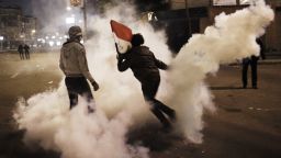 An Egyptian protester throws a tear gas canister fired by security forces toward back riot police during clashes outside the Egyptian Presidential Palace on Friday, February 1 in Cairo, Egypt.