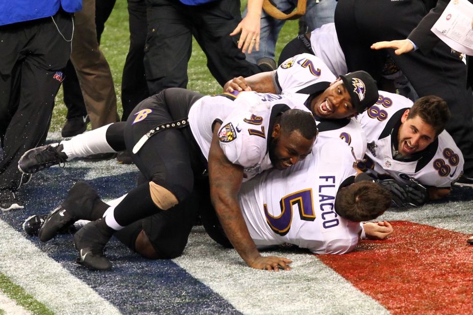 Quarterback Joe Flacco is tackled by teammates while celebrating after the game.