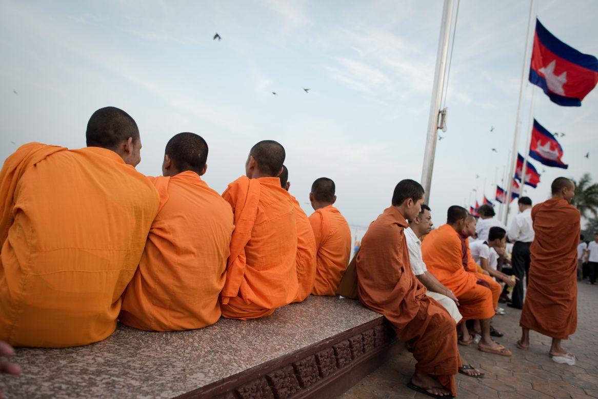 Cambodian Buddhist monks sit on the Mekong river bank as mourners gather to pray and pay their respects for the late former king on Sunday.