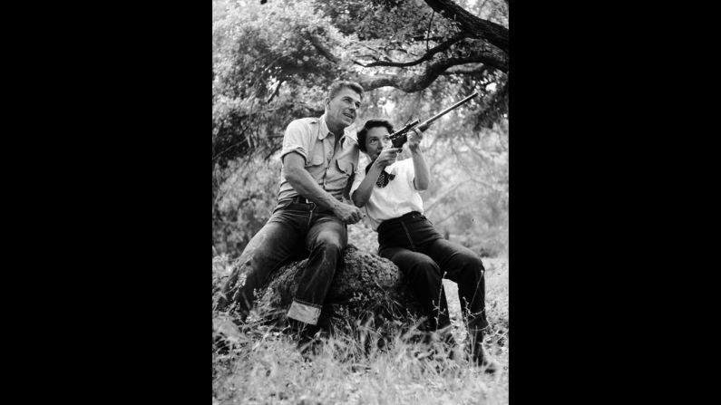 Ronald Reagan watches as his wife, Nancy, aims a rifle at their ranch in Malibu, California, in 1954.