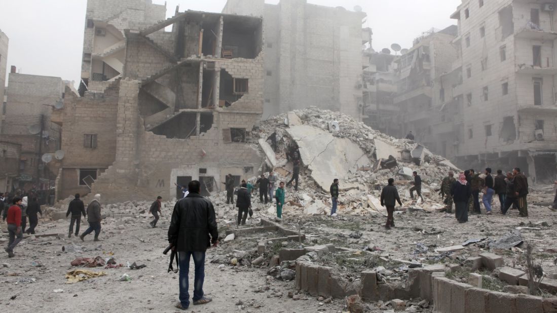 People stand in the dust of a building destroyed in an airstrike in Aleppo, Syria on February 3.