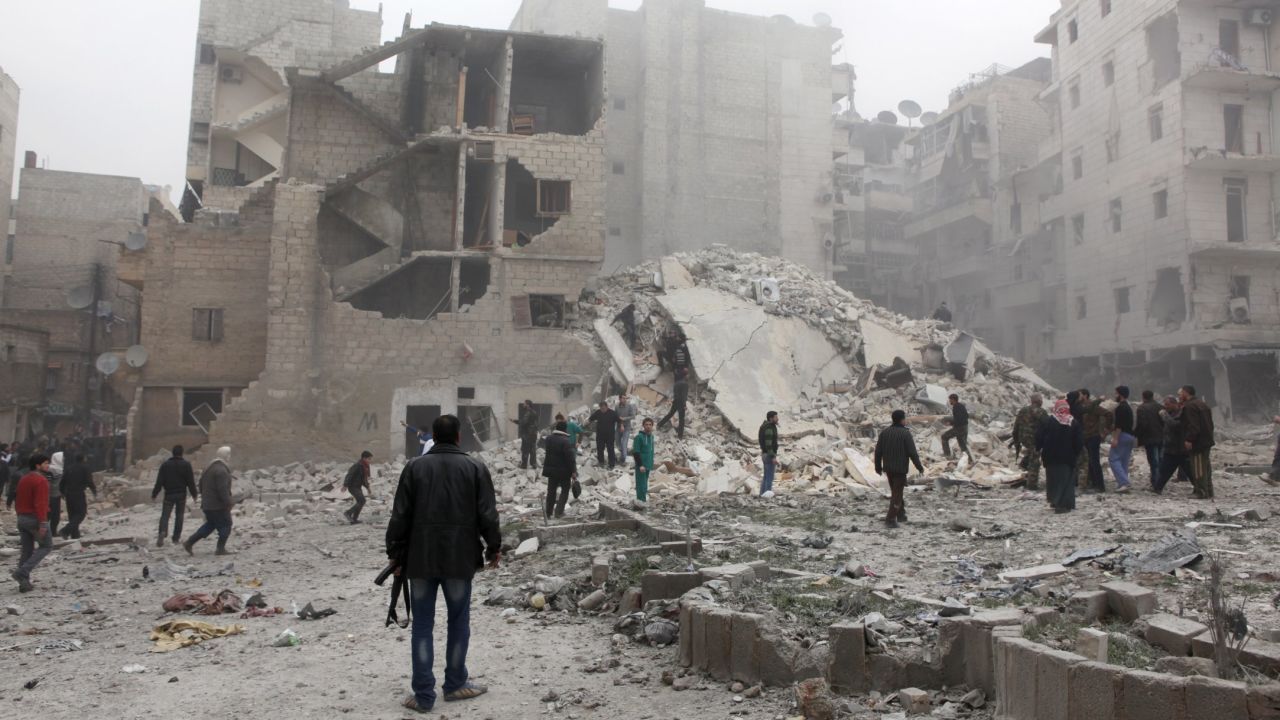 People stand in the dust of a building destroyed in an airstrike in Aleppo on February 3.