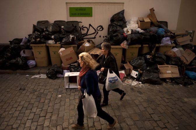 Two women walk past trash piles on February 4.