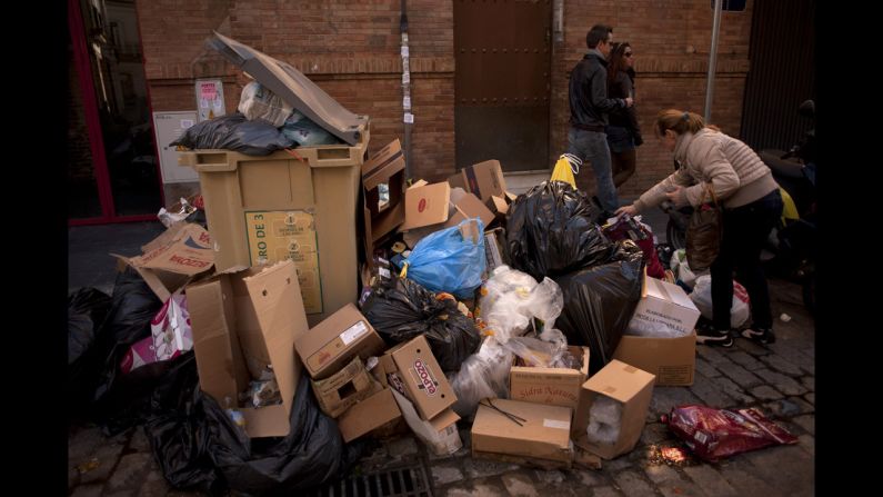 A woman pulls a plastic bag from uncollected rubbish on February 4.