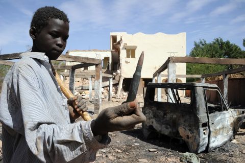 A child holds up a machine gun round found in the ruins of a building destroyed by French airstrikes in Douentza, Mali, on February 5.