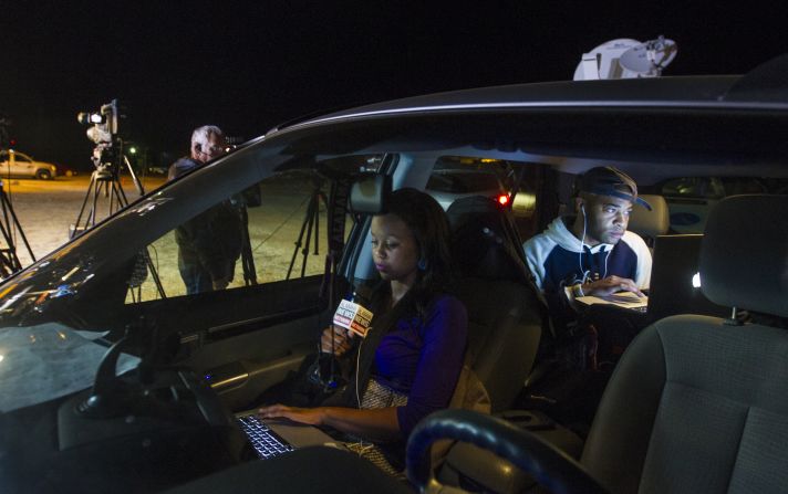 Reporter Ashley Thompson, left, and Marcus Effinger work on a report for Alabama News Network from their vehicle at the site of the standoff on February 4.