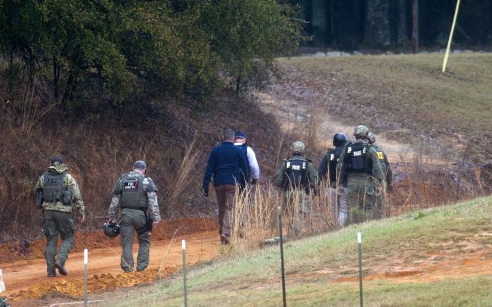 Law enforcement officers walk down a dirt road to the bunker to process the crime scene on Tuesday, February 5, after the standoff ended.