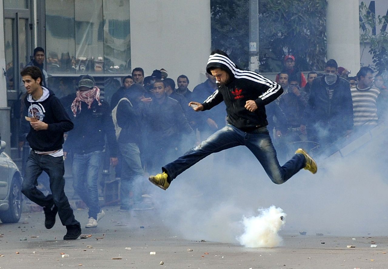 A Tunisian protester jumps amid smoke after police fired tear gas during a rally outside the Interior ministry in Tunis.
