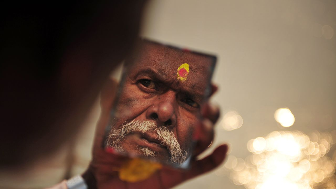 A Sadhu looks in a mirror as he applies paint to his forehead moments after taking a dip in the Ganges river in Allahabad during the beginning of Kumbh Mela in Allahabad on January 13.