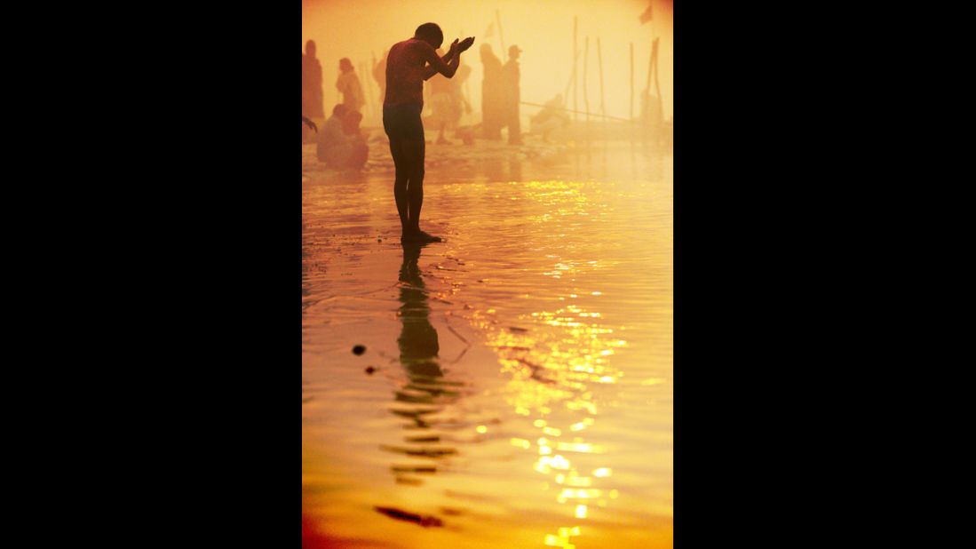 A devotee prays at day break while taking a dip at the Sangam on January 13.