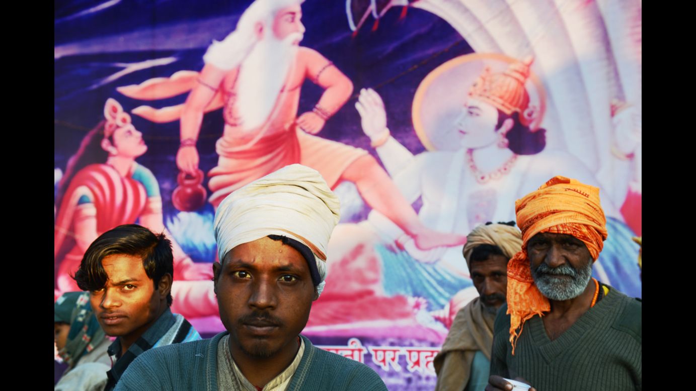 Indian devotees stand in front of a painting depicting Hindu gods during the Maha Kumbh Mela festival on February 8.